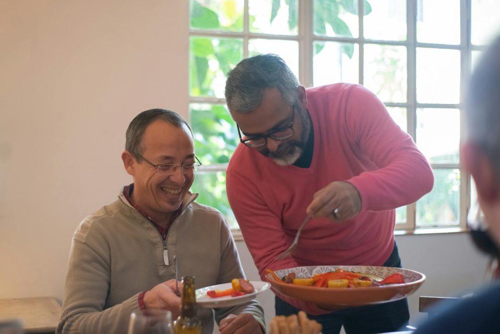 Image via https://www.pexels.com/photo/elderly-men-holding-ceramic-plates-with-food-while-having-conversation-6950755/